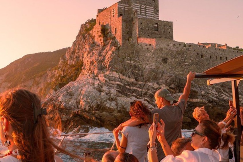 A group of people on a boat, a stone castle on a cliff, and a rocky coastline. 5