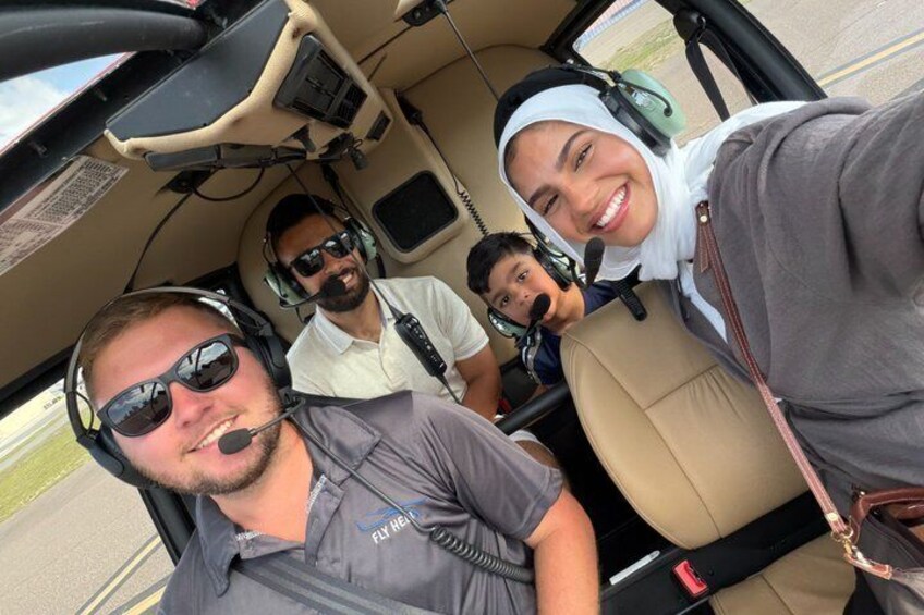 En helikoptercockpit med tre personer som bär hörlurar, en kontrollpanel och en utsikt över omgivningen. 5