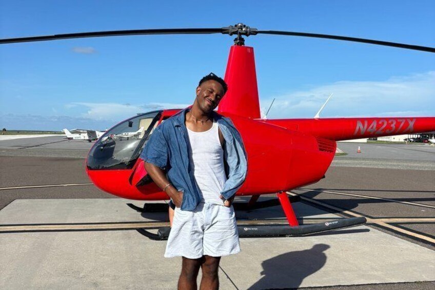 En person står framför en röd helikopter med registreringsnummer N4237X. 4