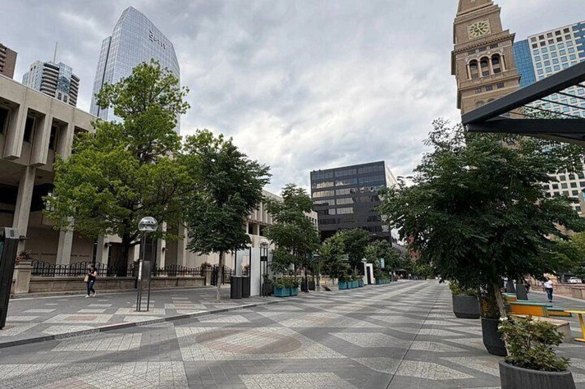 A city square with modern buildings, trees, and a clock tower. 2
