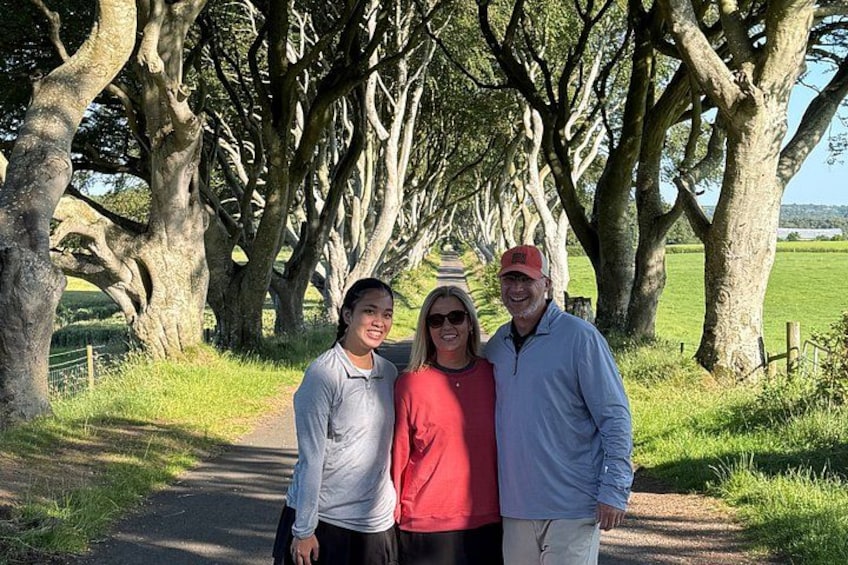 Three people standing on a path with trees in the background. 3