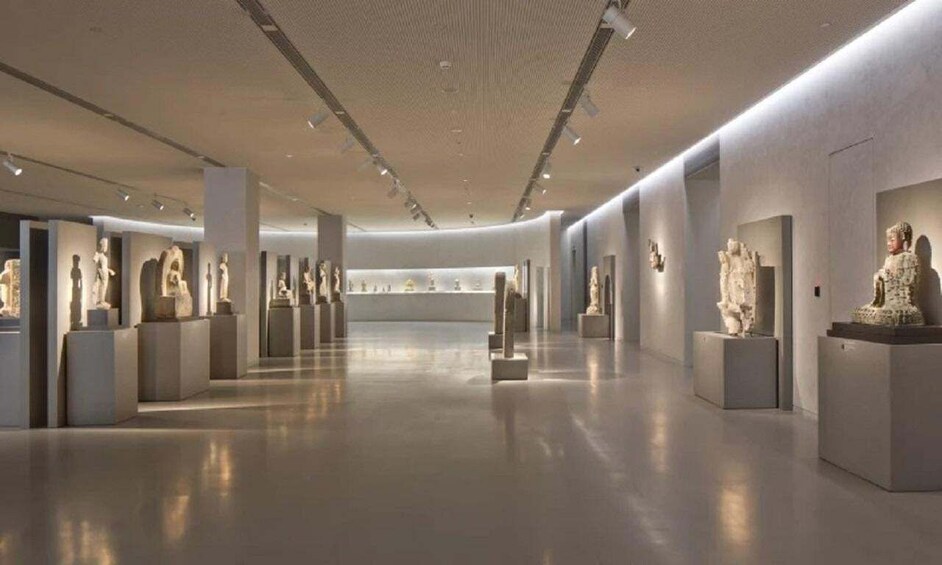 A museum interior with sculptures on pedestals. 1