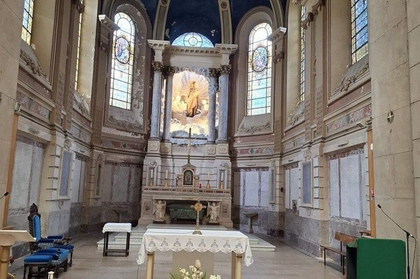 A church interior with a central altar, stained glass windows, and a statue. 2