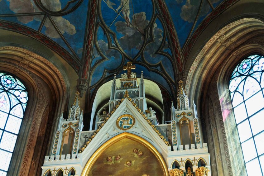 A Gothic-style church interior with ornate stained glass windows, a large central altar, and intricate ceiling artwork. 5