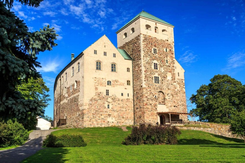 A large stone castle with a prominent tower, surrounded by lush greenery and a clear blue sky. 1
