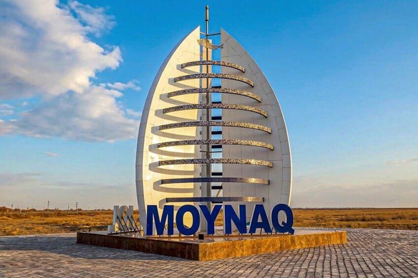 A large, white, sail-shaped structure with the text 'MOYNAQ' at its base. 1