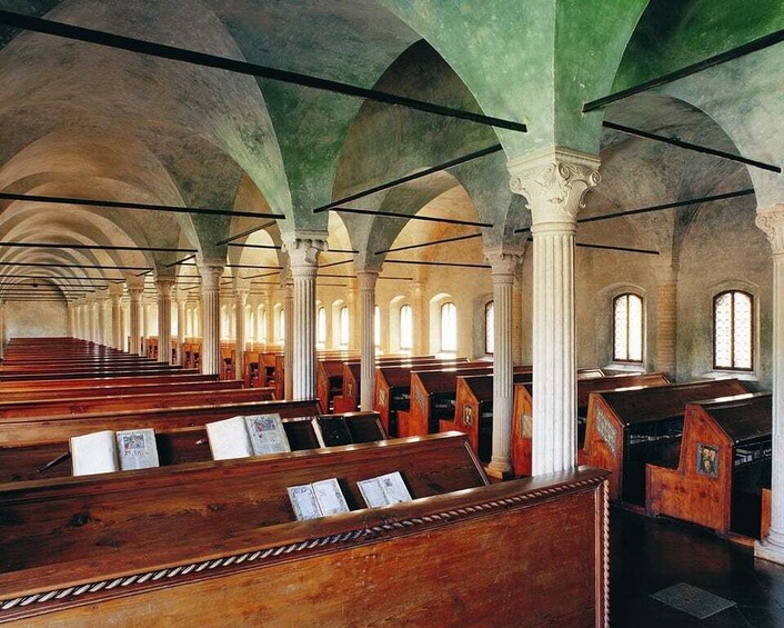 An interior of a church with wooden pews and green-painted arches. 2