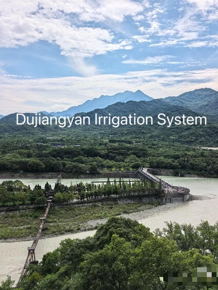 Un río con un puente, abundante vegetación y montañas al fondo. 3