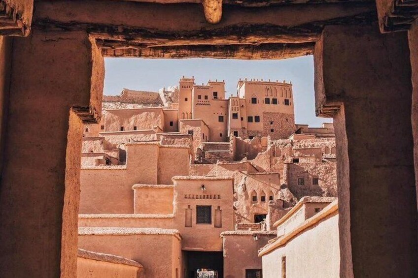 A view through an archway of a traditional building complex with multiple levels and a prominent tower. 3