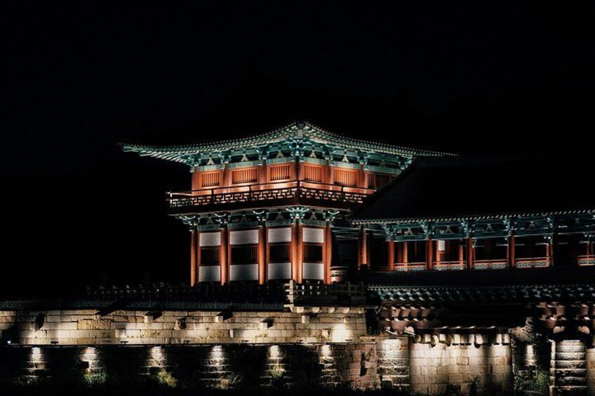En traditionel koreansk bygning om natten med oplyste bygninger og en stenbro i forgrunden. 2