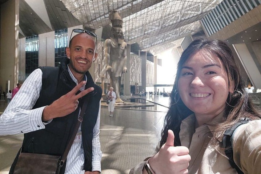 A modern indoor space with a glass ceiling, a large sculpture, and a person giving a thumbs-up. 2