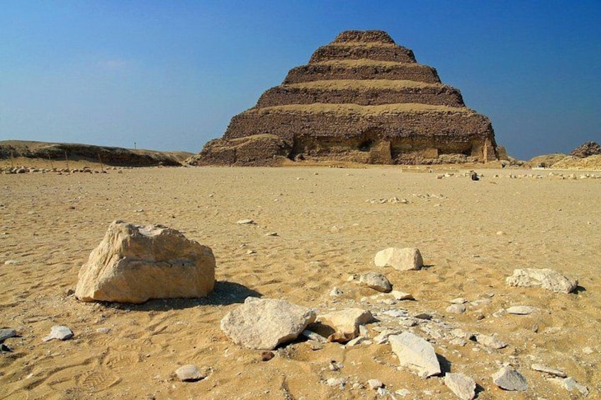 A large pyramid structure in a desert landscape with scattered rocks. 1