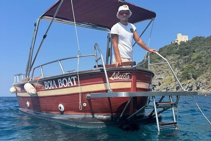 A red boat named 'BOIA BOAT' with a person standing on it, a ladder, and a rocky landscape in the background. 3
