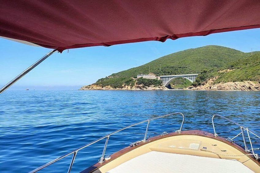 A boat on water with a bridge and green hills in the background. 5