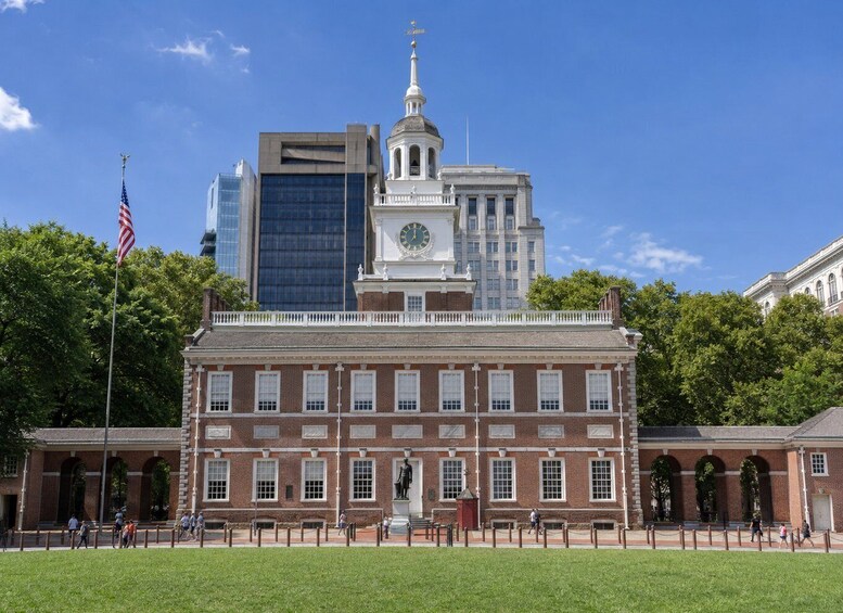 A historic building with a clock tower, surrounded by modern skyscrapers and a flag. 4