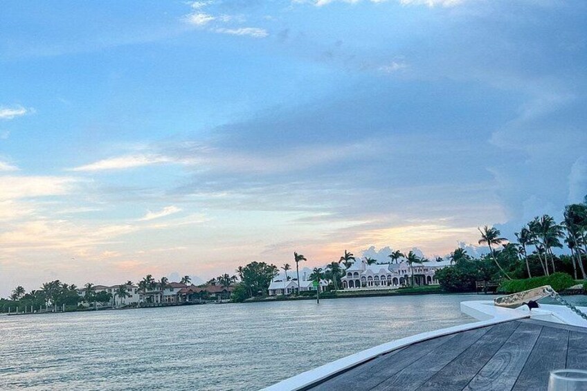 A waterfront view with a large white building, palm trees, and a clear sky. 2