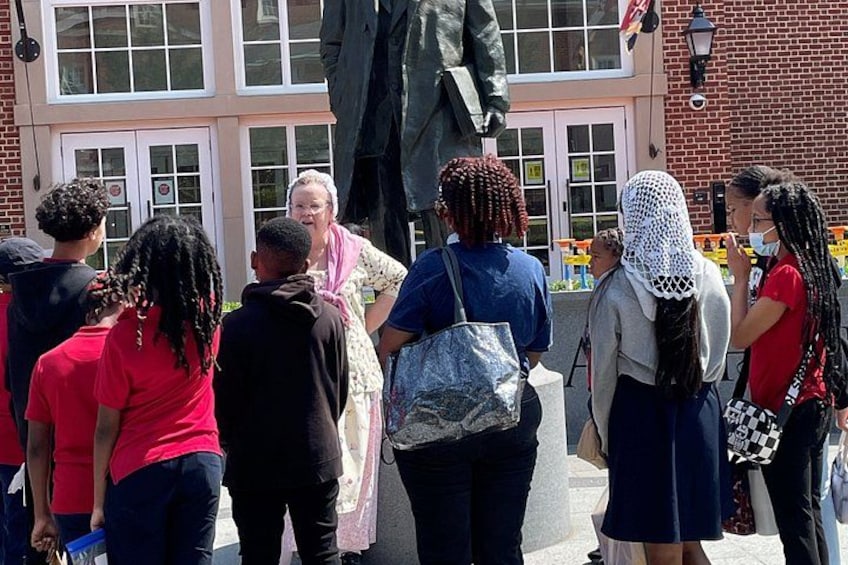 A group of people standing in front of a building with a statue. 3