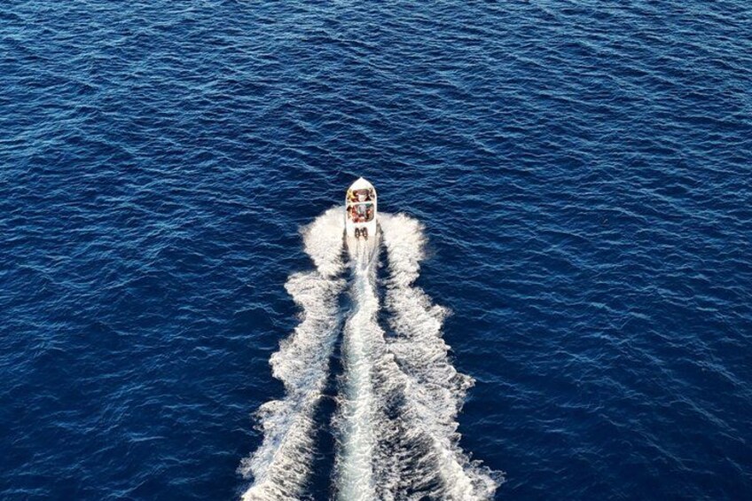 A boat speeding across a deep blue ocean, creating a wake behind it. 3