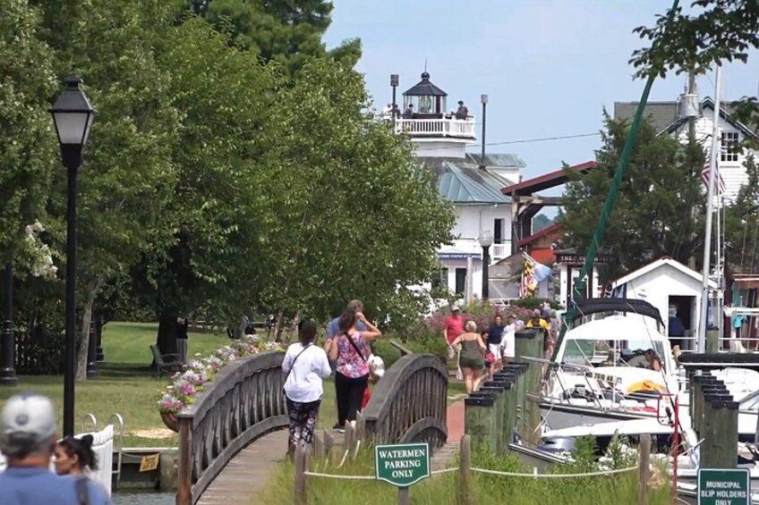 A wooden bridge over a waterway, a boat docked on the right, and a building with a tower in the background. 3