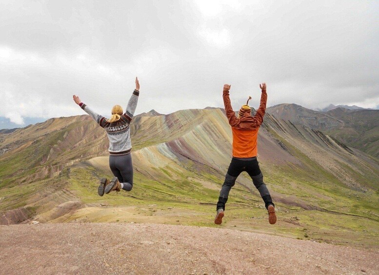 Twee personen springen in een bergachtig landschap. 4