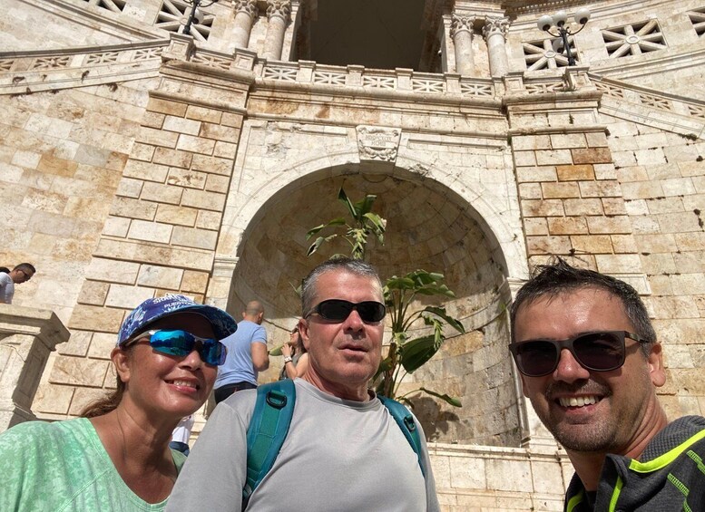 A group of people standing in front of a stone archway with intricate carvings. 2