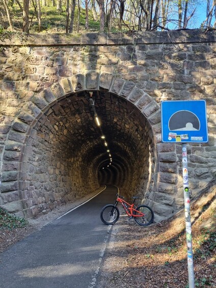 Kivestä rakennettu tunneli, jonka sisäänkäynnin luona on pyörä. 1