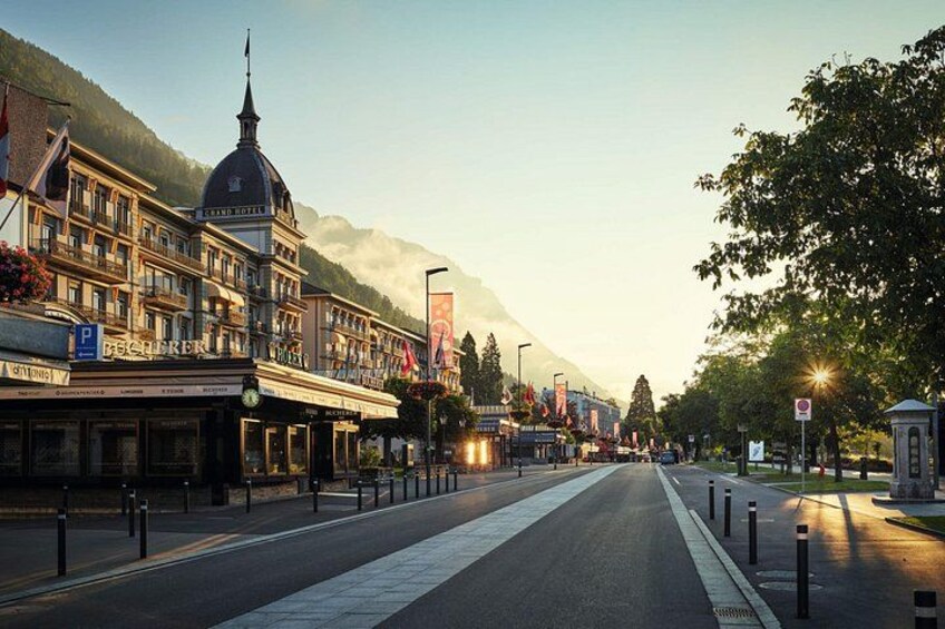 A street with buildings, a road, and mountains in the background. 2