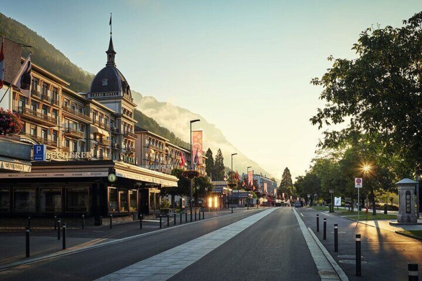 A mountain town street with buildings, a clear sky, and a mountain in the background. 2