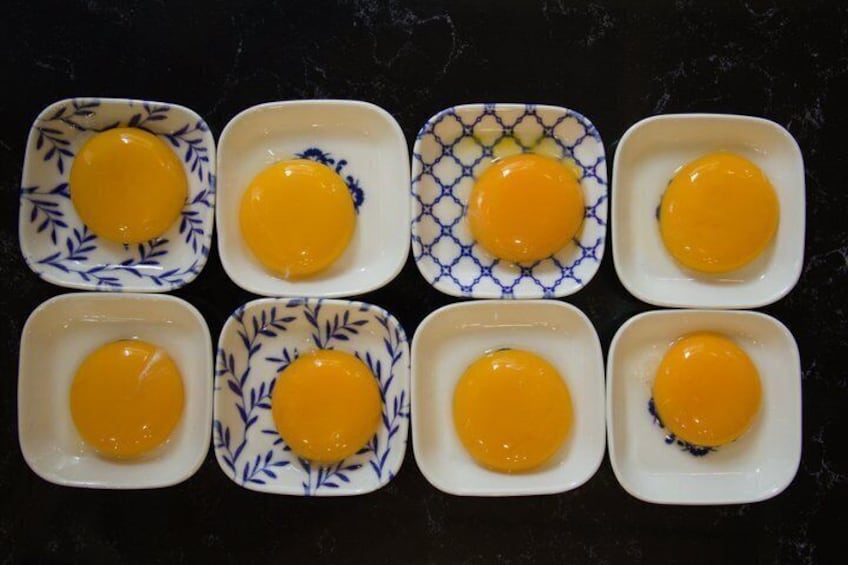 Seis platos cuadrados con un diseño azul, cada uno con una yema de huevo cruda. 3
