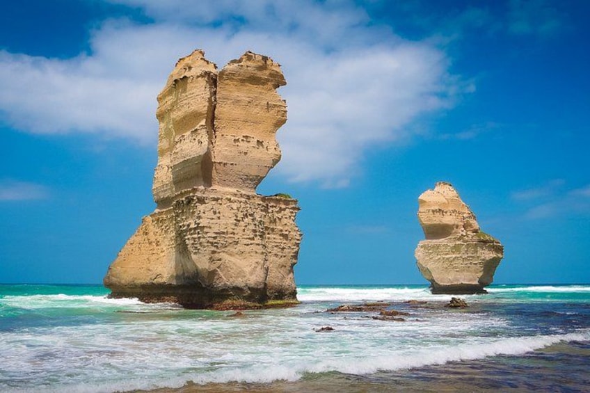 Two rock formations by the sea under a clear sky. 4