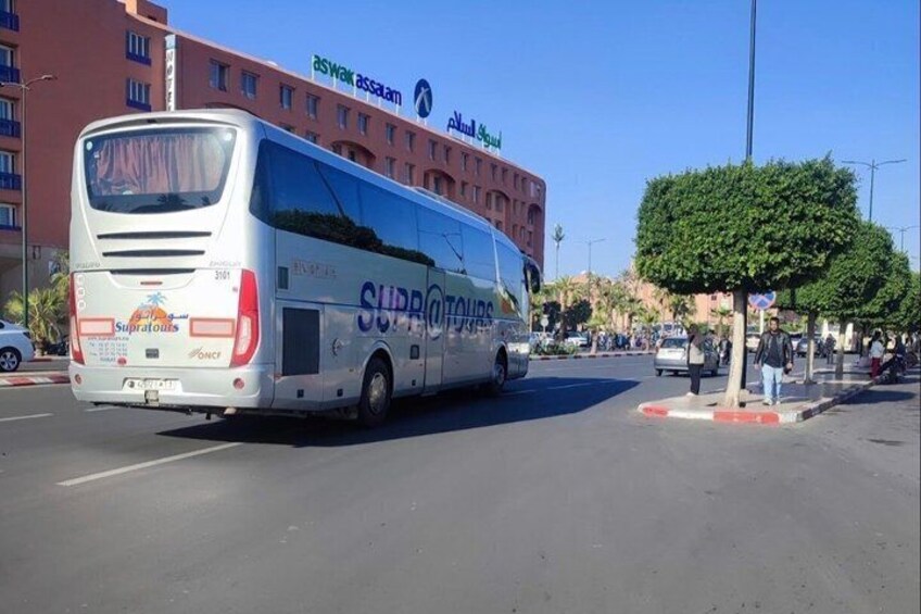 A white bus with 'SUPROTAURIS' on the side driving on a road. 5