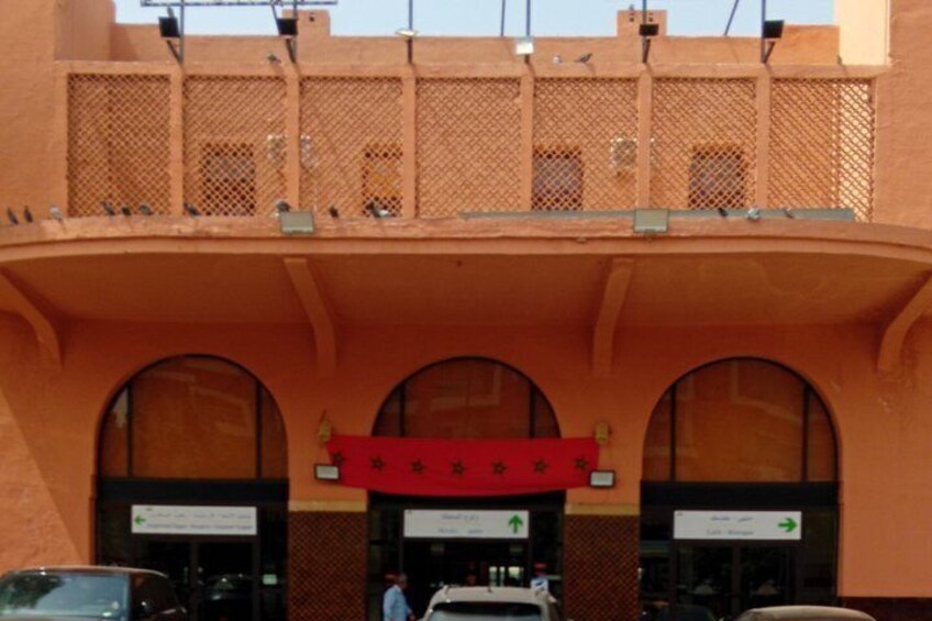 A building with a red awning, arched windows, and a mesh balcony. 3