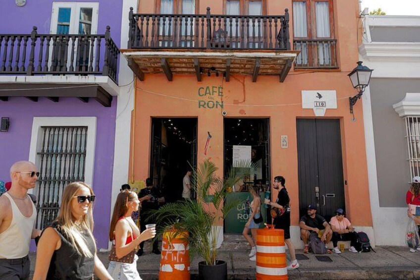A cafe named 'Cafe Ron' with outdoor seating, a palm tree, and a striped bollard. 4