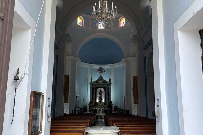 A church interior with pews, a chandelier, and stained glass windows. 2