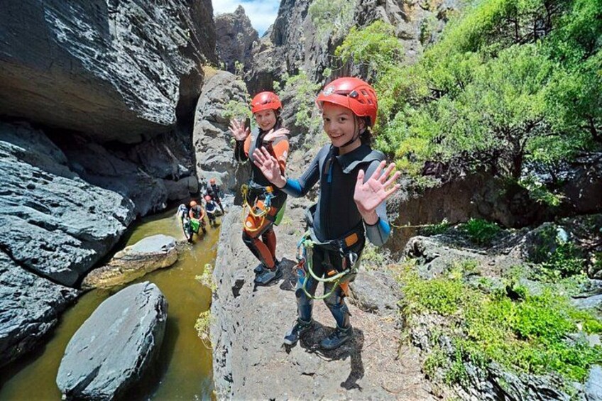 A group of people rappelling down a rocky cliffside with a river below. 1