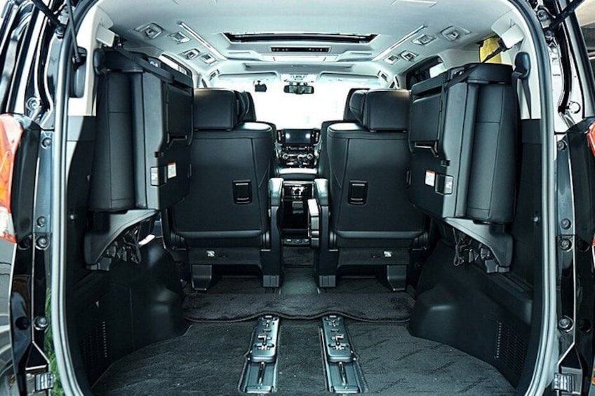 A vehicle interior with two rows of black seats, a central console, and a rearview mirror. 3