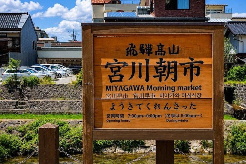 A wooden signboard with Japanese text and English translation for the Miyagawa Morning Market. 4