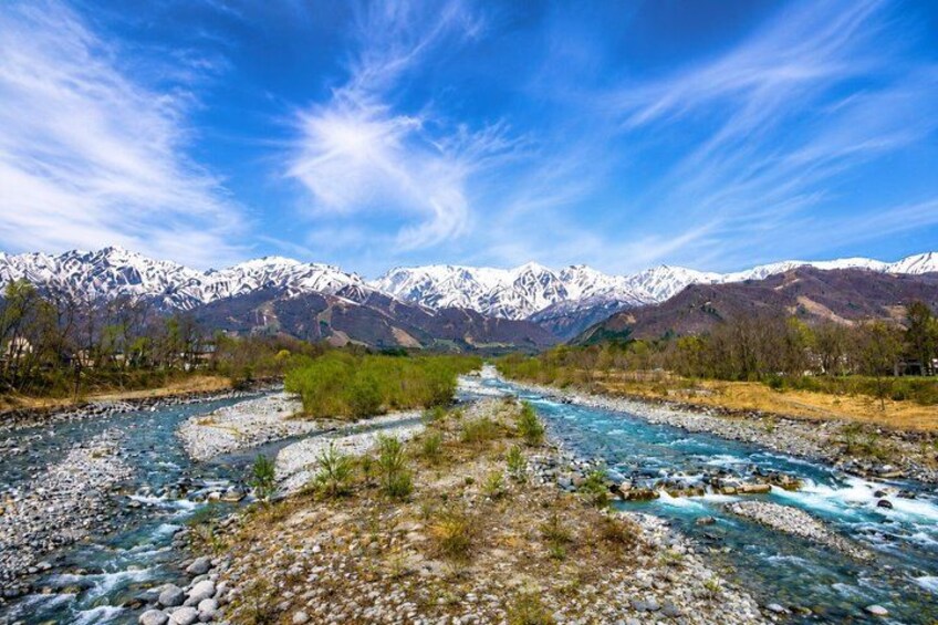 A river flowing through a mountainous landscape with snow-capped peaks in the background. 2