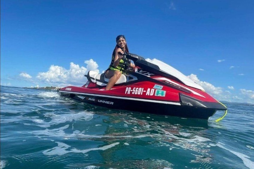 A person riding a red and black jet ski on clear blue water. 5