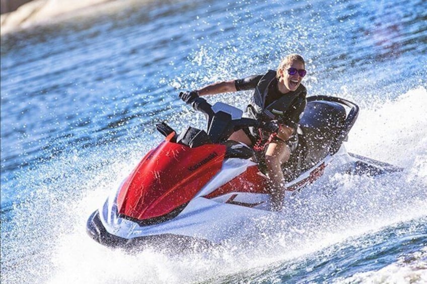 A person riding a red and white jet ski on water. 2