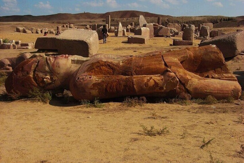 A desert landscape with ancient stone structures and a large, weathered sarcophagus. 1