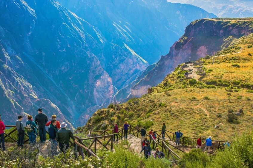 Un grupo de personas en un sendero de montaña con vista a un cañón profundo. 1