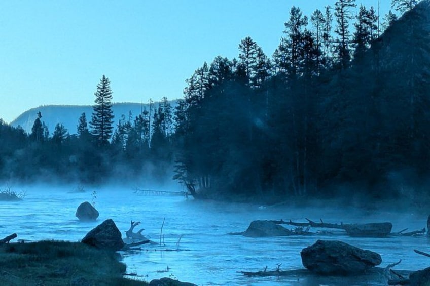 Un río con rocas, árboles y niebla. 3