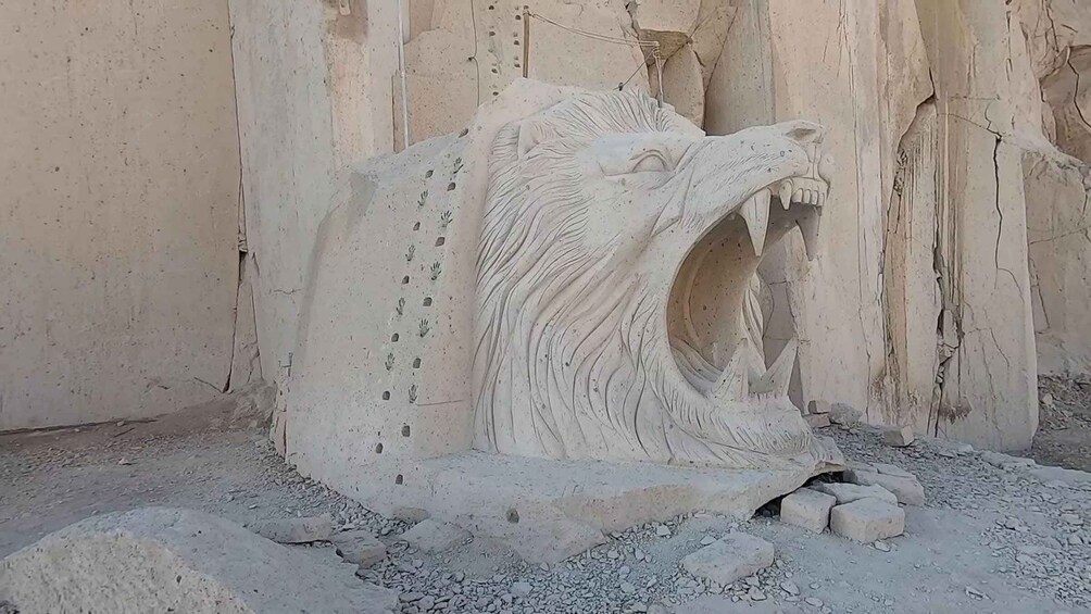 Una gran talla de piedra de un león rugiente, con expresión amenazante, sobre un fondo rocoso. 3