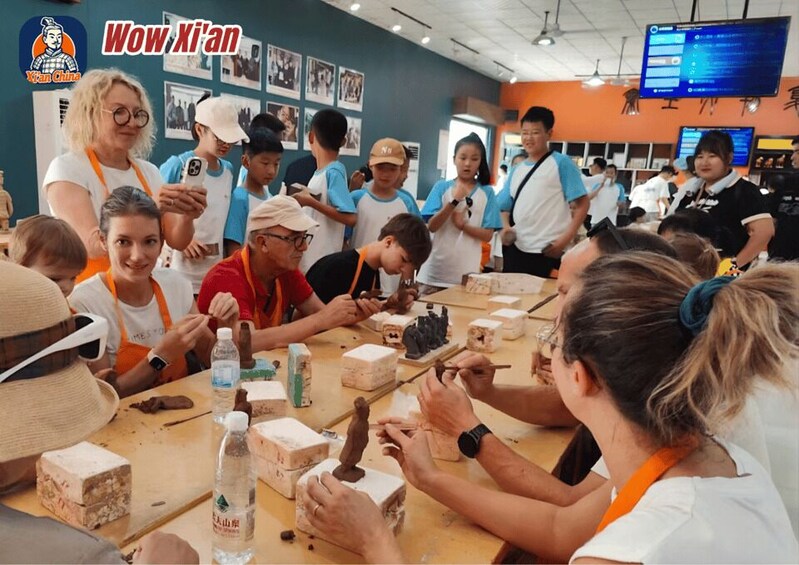 A group of people engaged in a pottery workshop, with clay sculptures and tools on the table. 2