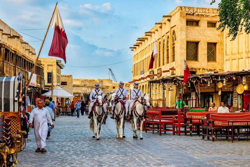 A street scene with horse-drawn carriages, traditional buildings, and flags. 1