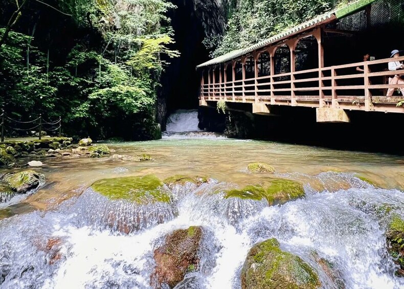A wooden bridge over a flowing river with a waterfall in the background. 5