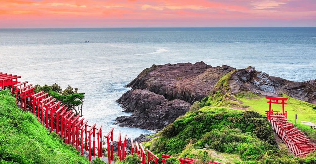 A coastal landscape with red torii gates, rocky cliffs, and a view of the ocean. 1