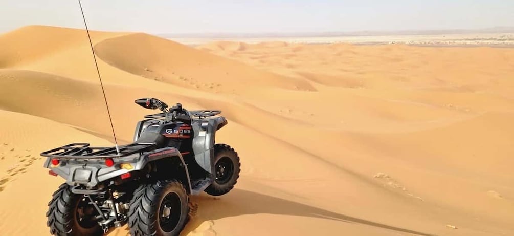 A quad bike in a desert with sand dunes. 1