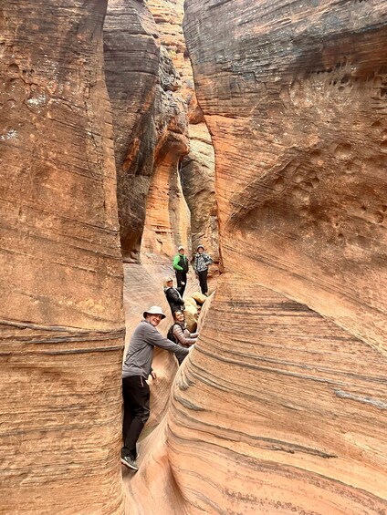 People hiking in a narrow canyon with layered rock formations. 5